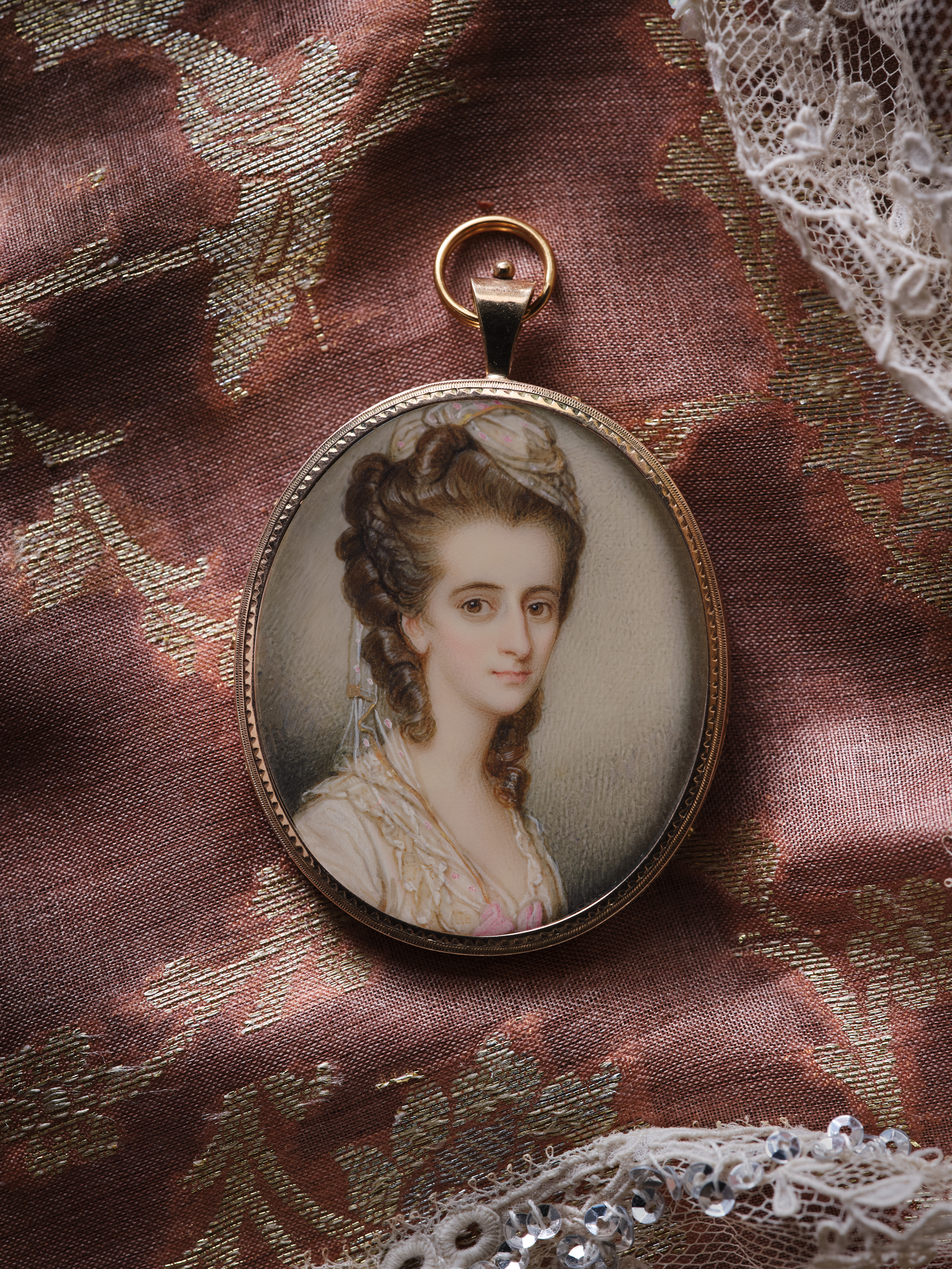 Portrait miniature of a Lady, wearing lace dress with pink embroidery, pink satin bow, a matching turban in her brown hair