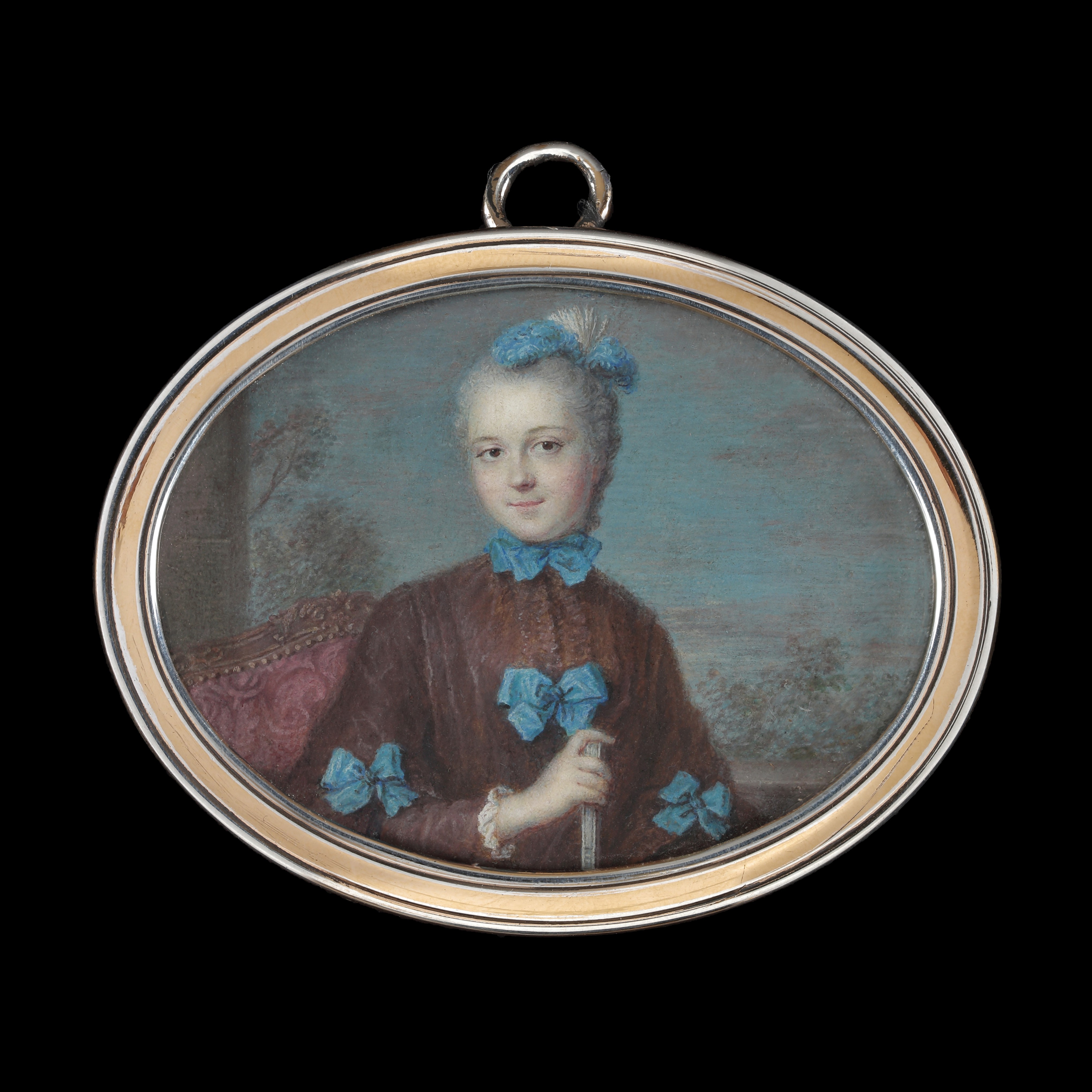Portrait miniature of a Lady, wearing a brown coat with fur lining, tied with blue ribbons, blue feathers in her hair, holding a fan, seated against a landscape background; circa 1760s 
