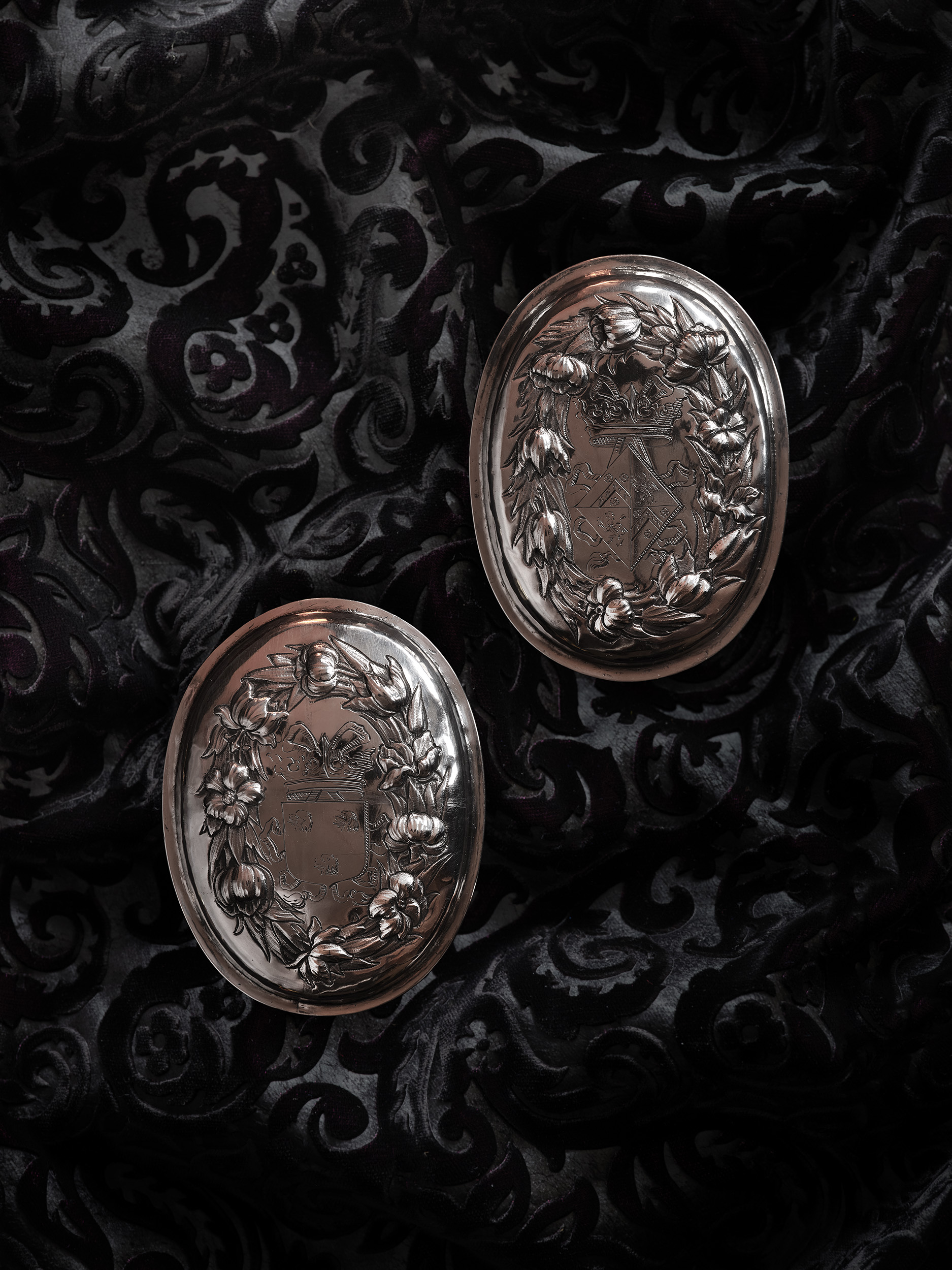 A pair of oil portraits, presumably Husband and Wife; he wearing armour, lawn collar and a red sash around his arm; she wearing lace-trimmed blue dress with diamond and pearl brooch, pearls and pearl-drop earrings