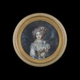 Portrait miniature of a Lady, standing in a wooded landscape, wearing a white dress with a tiered lace collar and yellow bodice, decorated with bright blue ribbons, flowers in her hair and at her corsage