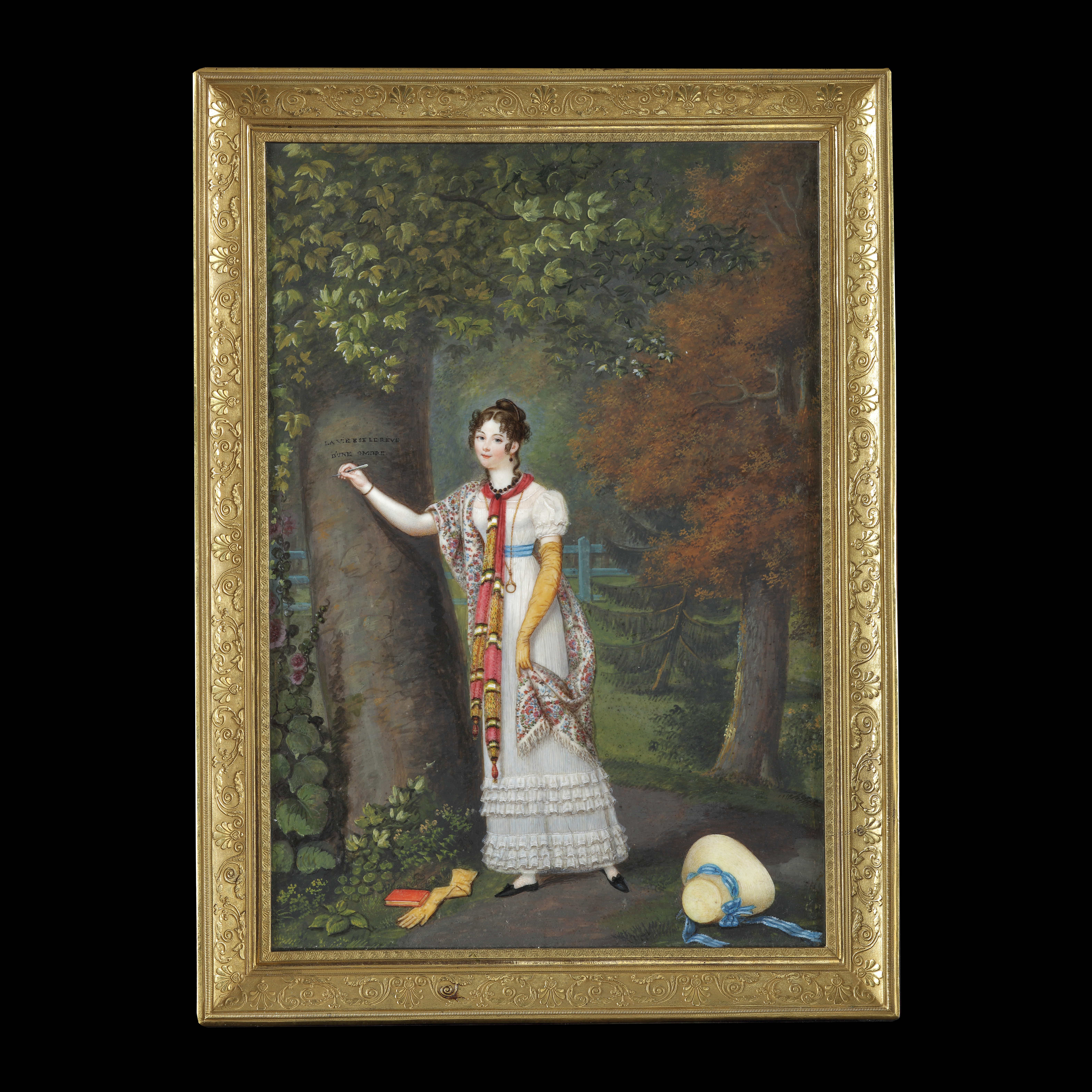 Portrait miniature of a lady stood in a wooded landscape, wearing a white dress, with a striped scarf and floral-pattern shawl, her hat and one of her gloves on the ground; circa 1815