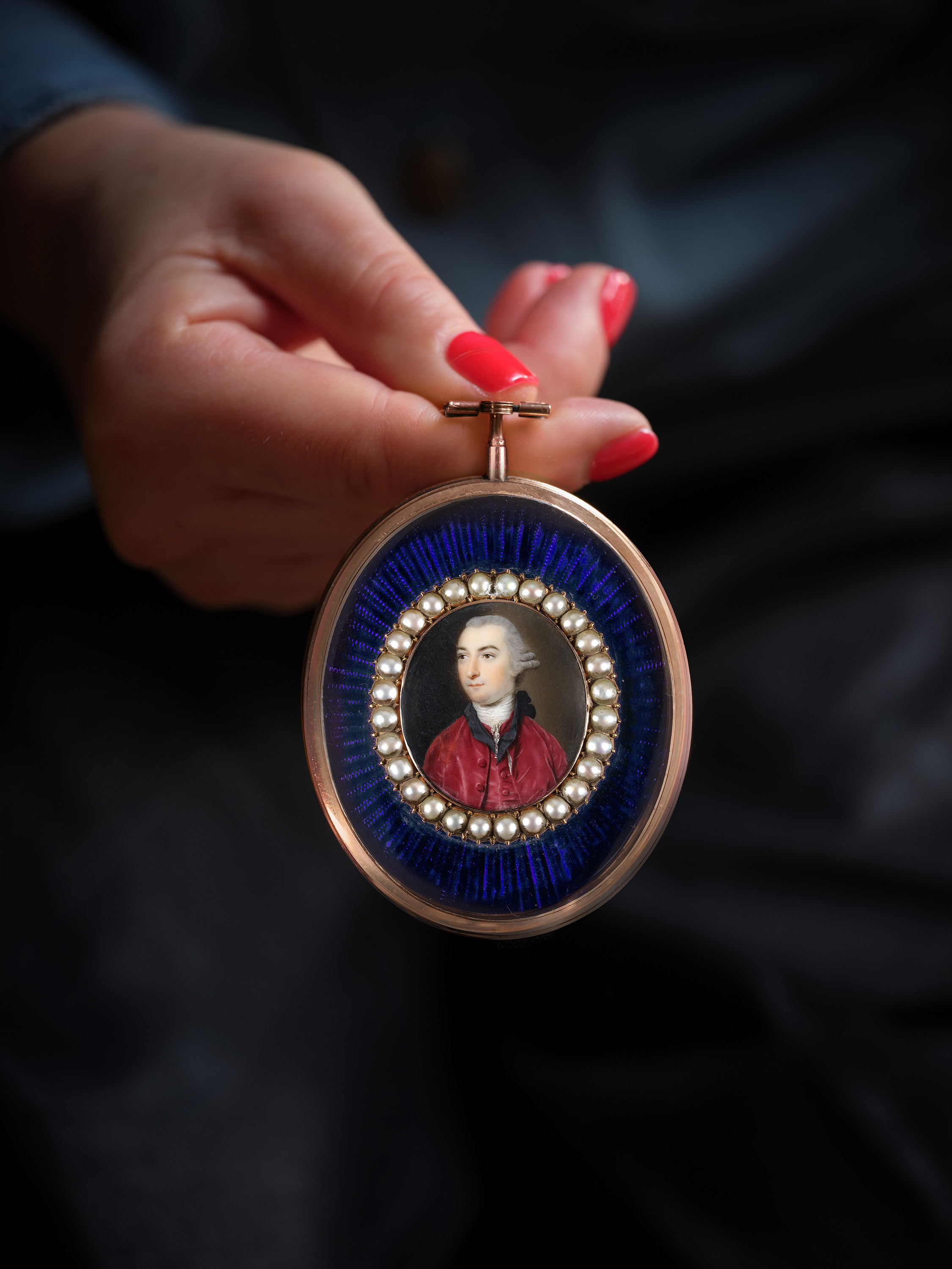A portrait miniature of a Gentleman with powdered hair en queue and tied with a black ribbon, wearing a white stock and crimson velvet jacket and waistcoat