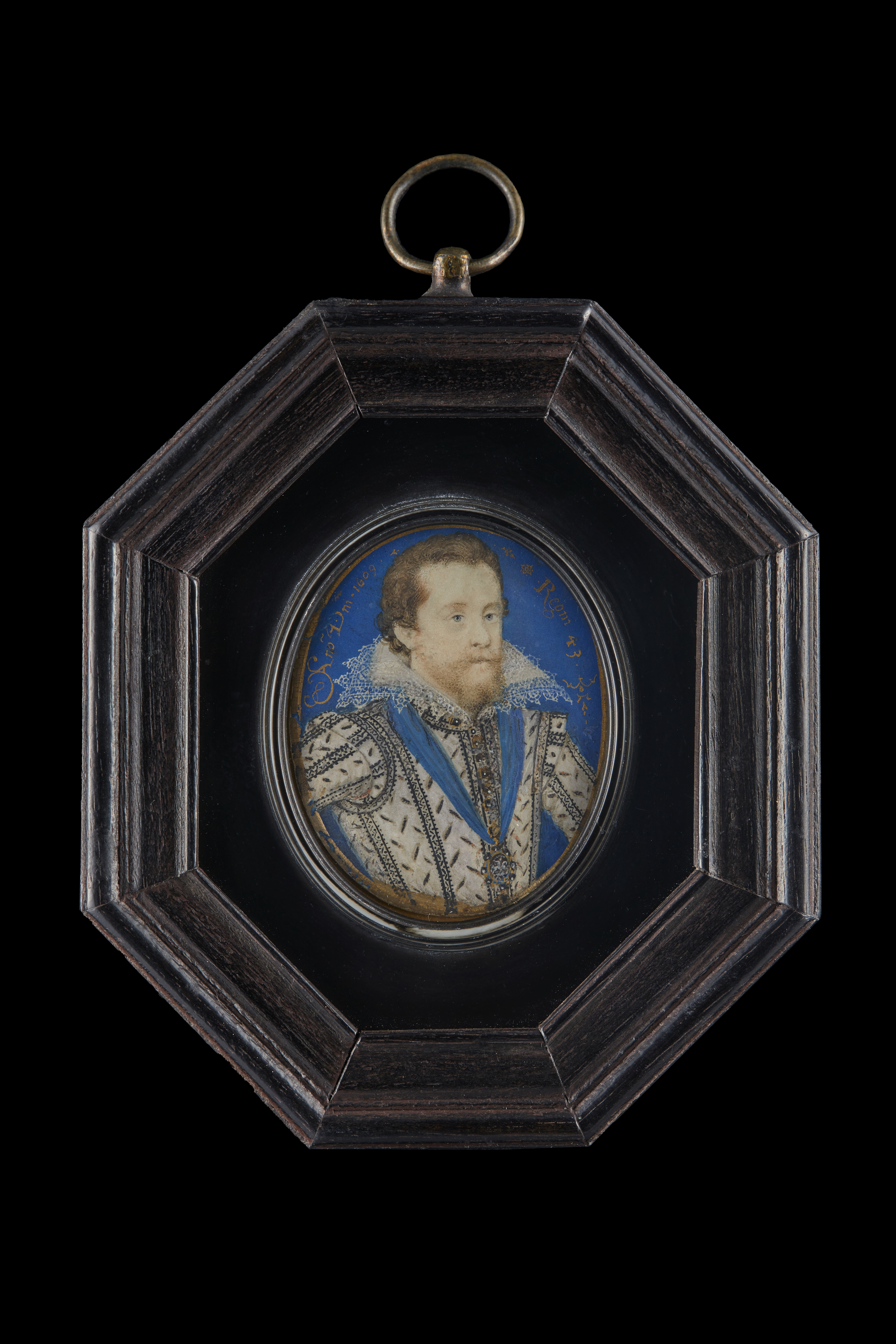 King James I of England and VI of Scotland (1566-1625), in white doublet, slashed on bodice and sleeves to reveal black, jewel-set gold buttons, white lace upstand collar, wearing the Lesser George of the Order of the Garter on a blue ribbon around his neck; blue background with gold border, inscribed in gold in the blue background 'Ano Dmni 1609 / Regni 43'