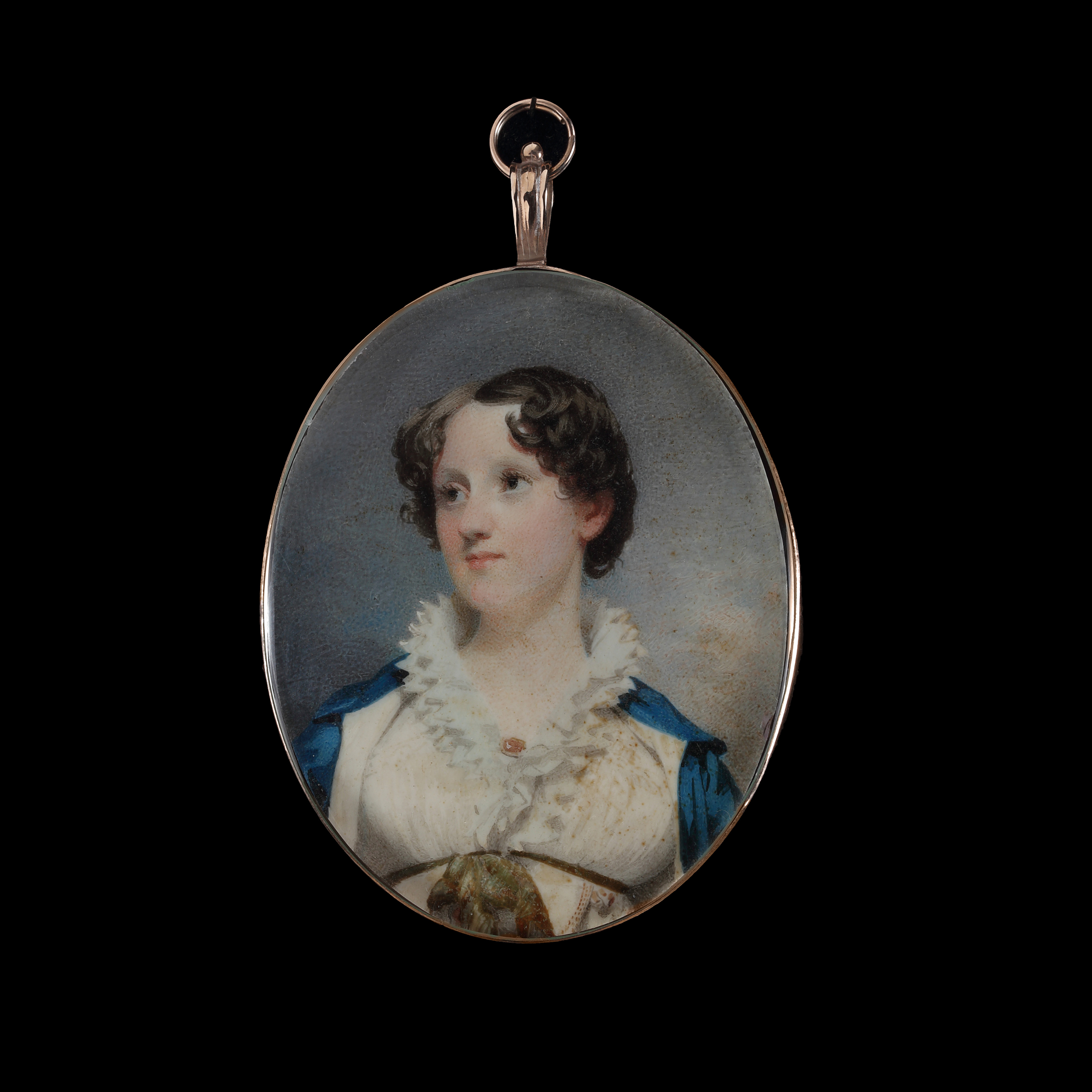 Portrait miniature of a Young Lady, wearing cream dress with white frilled collar and brooch, a green ribbon under her bust and cream-lined blue cloak, circa 1810