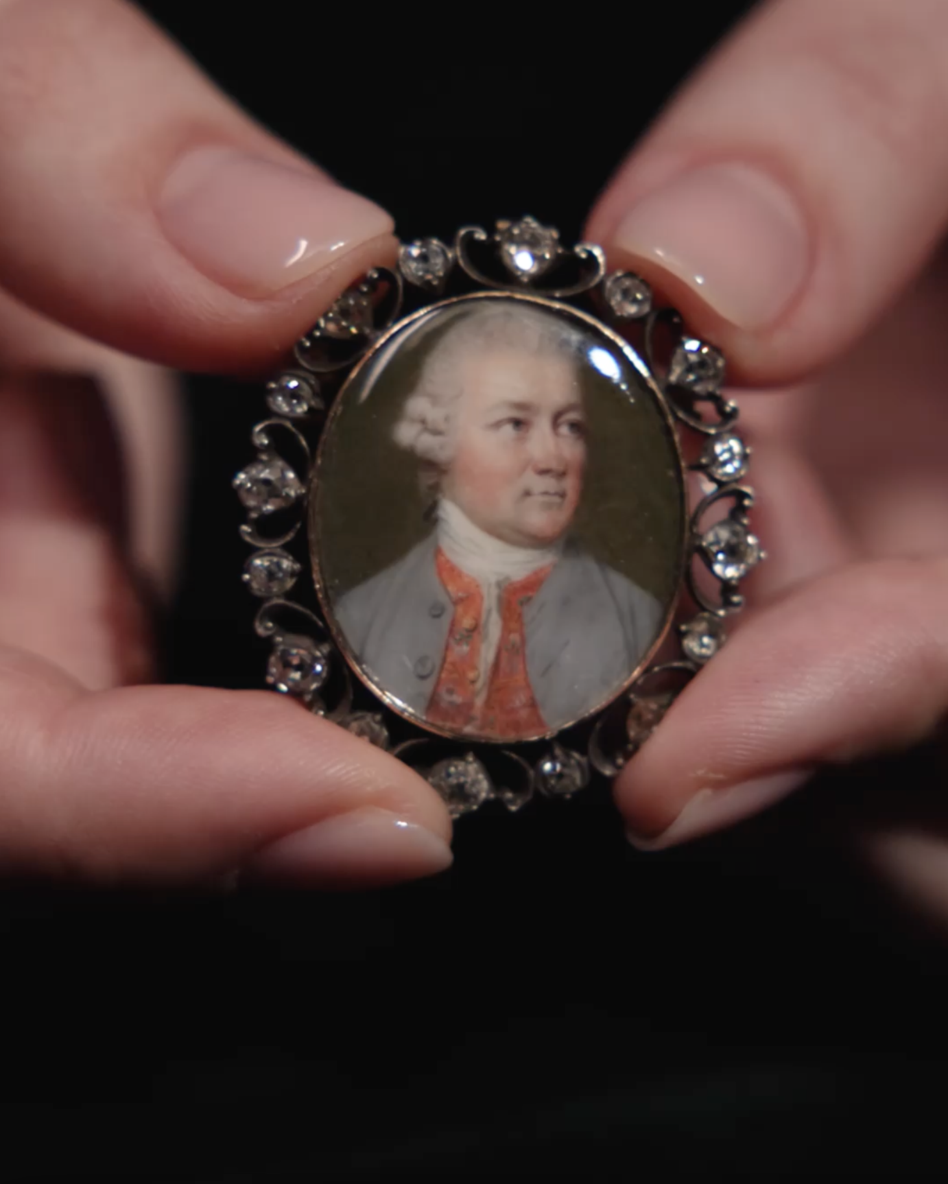 Portrait miniature of a Gentleman, wearing a pale grey coat, a scarlet waistcoat embroidered with flowers, and white stock, his powdered wig worn en queue
