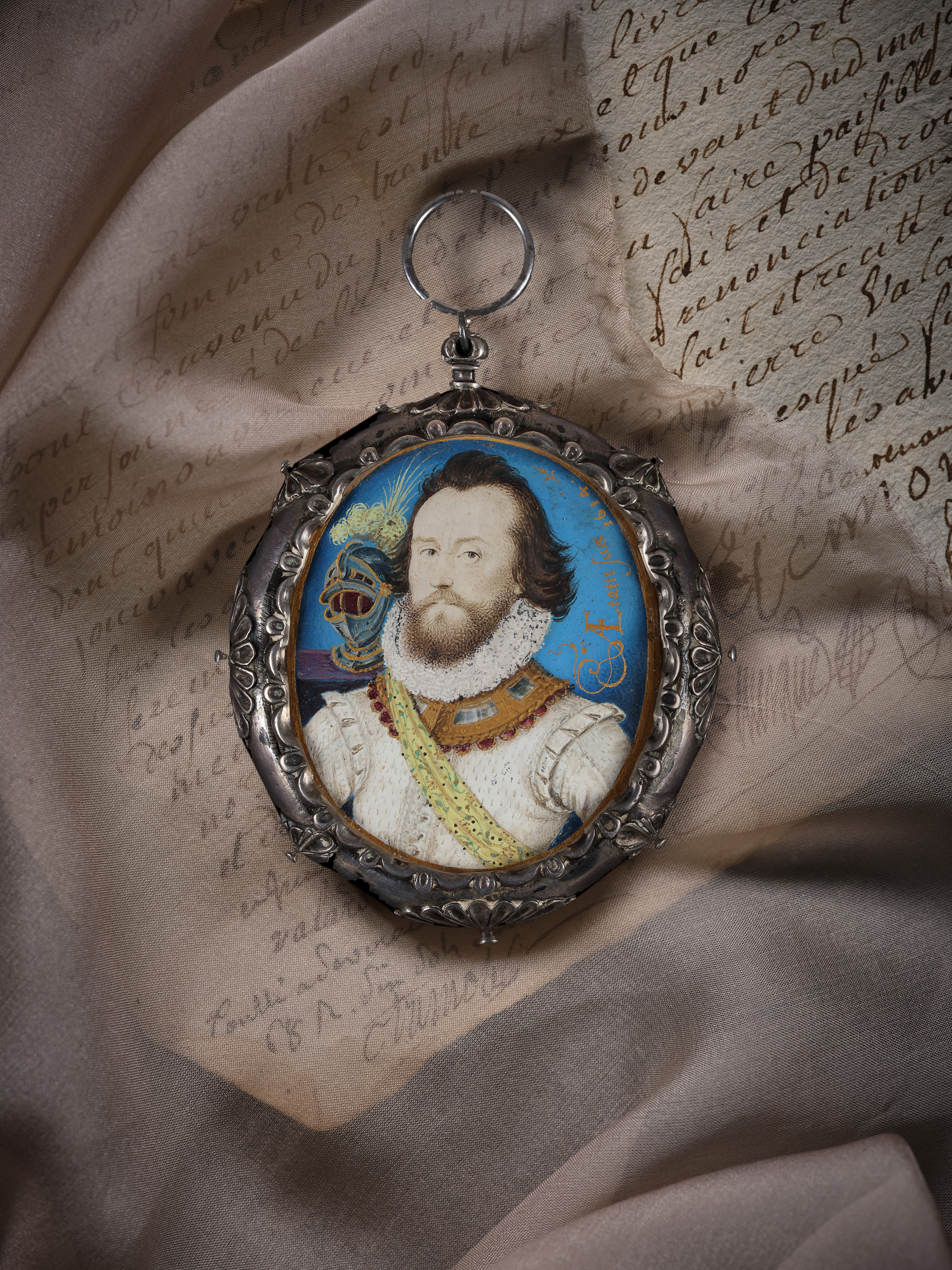 Portrait miniature of a Soldier, wearing white doublet and ruff, jewel-set gorget, yellow embroidered sash and gilt-banded helmet with white plumes on a purple velvet plinth behind