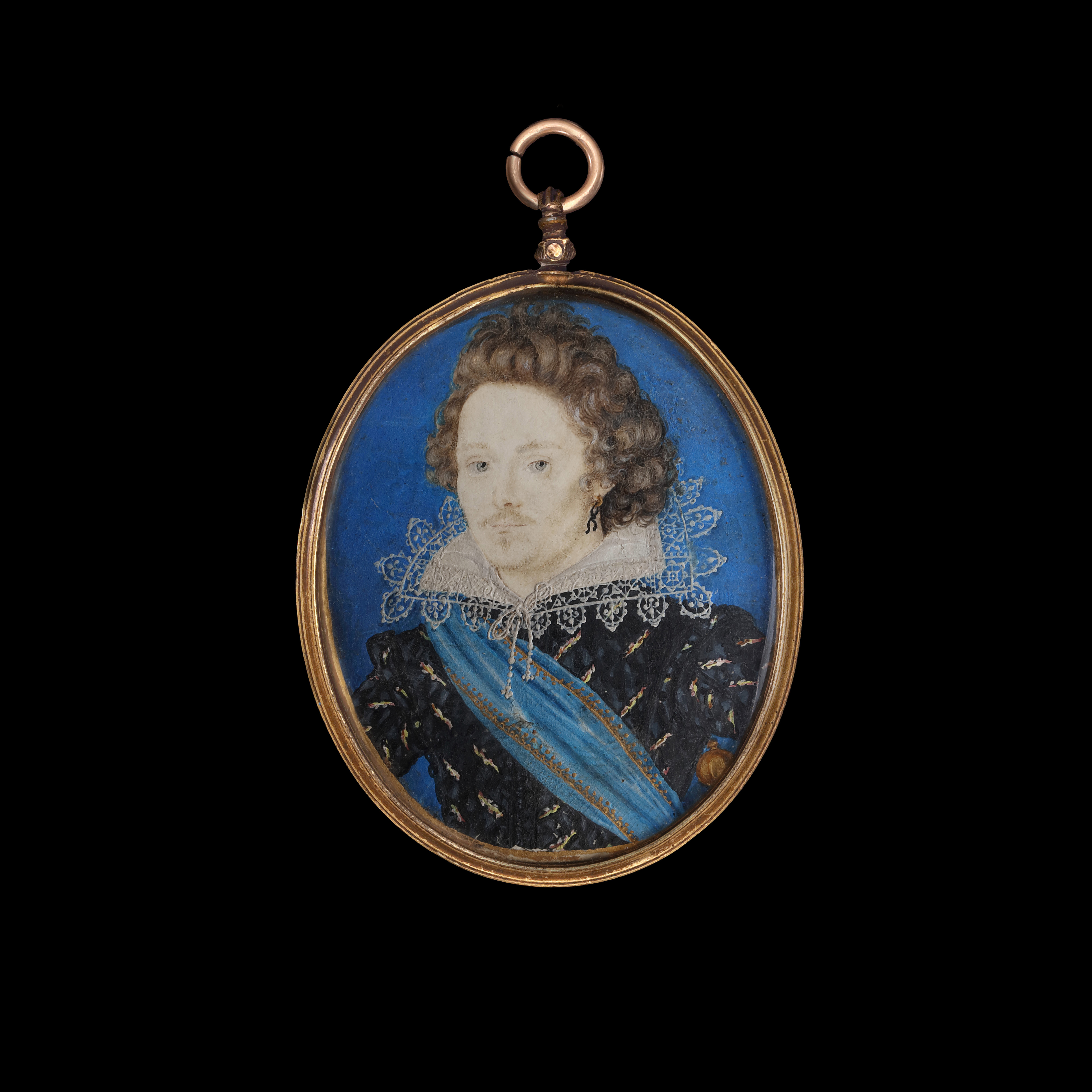 Portrait miniature of a Gentleman wearing a slashed black doublet, a standing collar edged with lace, a grey streak in his hair, a gold hoop earring with a black cord, a blue sash edged with gold embroidery, the pommel of a sword visible at his left side; with a blue background and a gold border